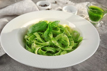 Plate of delicious pasta with pesto sauce on table