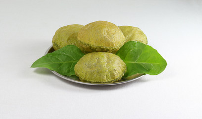 Palak poori, made from spinach puree and wheat flour dough is a popular Indian vegetarian breakfast, arranged as a stack on a steel plate with fresh spinach leaves.