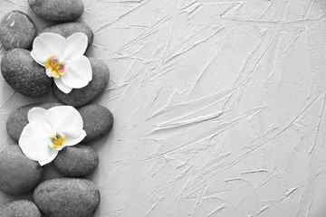 Spa stones and beautiful orchid flowers on grey textured background