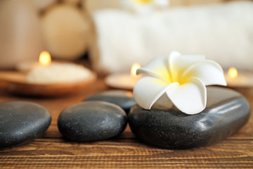 Spa stones and beautiful flower on wooden table, closeup