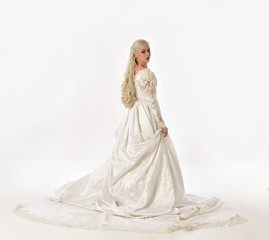 Fototapeta premium full length portrait of blonde woman wearing long white bridal gown. standing pose on white studio background.