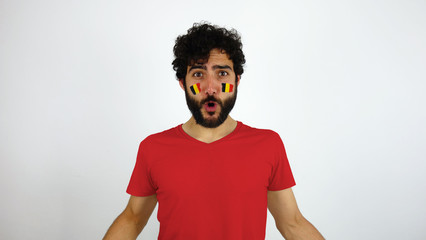 Sport fan celebrating a goal of his team. Man with the flag of Belgium makeup on his face and red t-shirt.      © Lia Aramburu