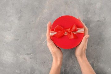Woman holding gift box on grey background