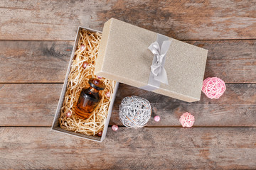 Open gift box with bottle of perfume on wooden background, top view