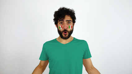 Sport fan celebrating a goal of his team. Man with the flag of Mexico makeup on his face and gren t-shirt.      © Lia Aramburu