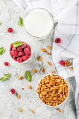 Healthy breakfast ingredients. Breakfast cereal, milk or yogurt glass, raspberries and mint on grey stone background, copy space top view