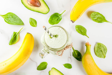 Healthy smoothie with banana and baby spinach, n white marble background copy space top view