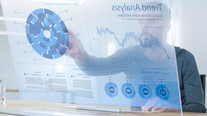In the Near Future Successful Trader Using Computer with Transparent Display that Shows Interactive Line, Charts and Other Useful Economic Statistics. His Office is Bright and Modern.