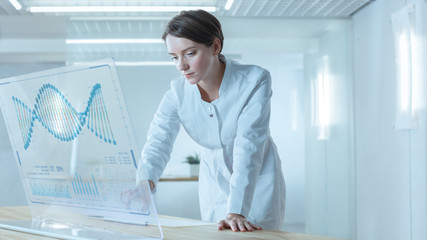 In the Futuristic Laboratory Female Scientists Working on Deciphering Sequenced Human DNA on the Transparent Display Computer.