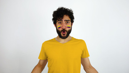 Sport fan celebrating a goal of his team. Man with the flag of Colombia makeup on his face and yellow t-shirt.      © Lia Aramburu