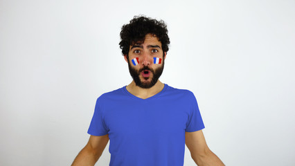 Sport fan celebrating a goal of his team. Man with the flag of France makeup on his face and blue t-shirt.      © Lia Aramburu
