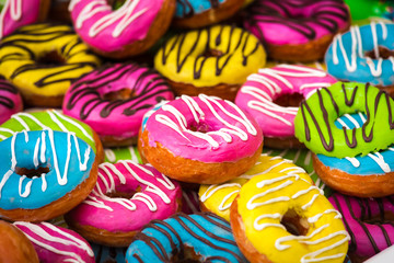 Many colorful donuts, background of different color cakes