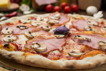 Delicious italian pizza with ham and mushrooms on wooden background