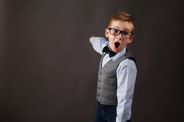 Obraz premium Shocked little boy in a suit shows something on the background