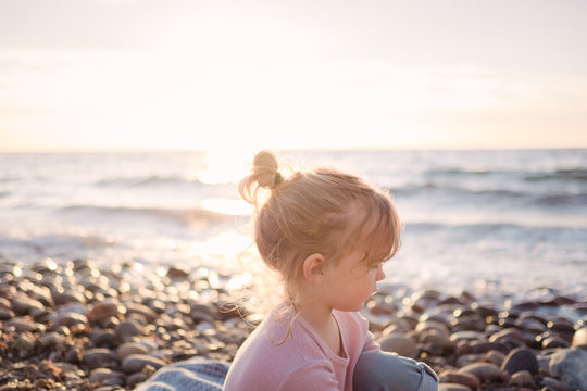 Kleines Mädchen bei Sonnenuntergang am Strand