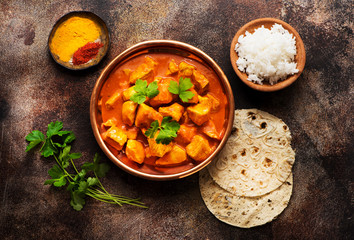 Spicy chicken tikka masala with rice, indian naan bread, spices, herbs. Indian dish.