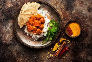 Indian dish Spicy chicken tikka masala with rice, indian naan bread, spices, herbs.