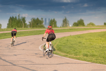 woman on sport bicycle in black helmet on road cycle scrape the curve