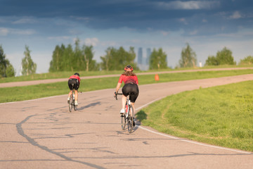 Obraz premium woman on sport bicycle in black helmet on road cycle scrape the curve