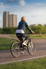 young beautiful woman riding a bicycle in a park. Active people. Outdoors