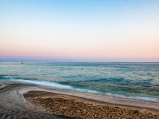 Soft pink sunset view of sea from sandy beach