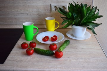 Red ripe tomatoes and green cucumbers lie on the kitchen table.