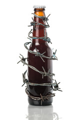 Dark beer bottle wrapped in barbwire on white isolated background. Stop alcoholism. Drink responsibly. Drink aware,