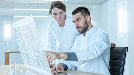 In the Futuristic Laboratory Male and Female Scientists Work on Transparent Computer Display. Screen Shows Sequenced Human DNA.