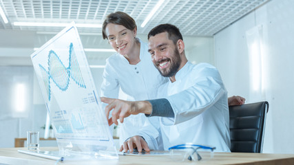 In the Futuristic Laboratory Male and Female Scientists Work on Transparent Computer Display and Joking. Screen Shows Structure of Human DNA.