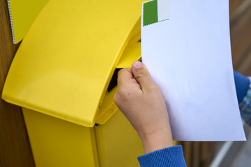 Childs Hand Puts Blank Postcard in An Italian Yellow Post Box Pi