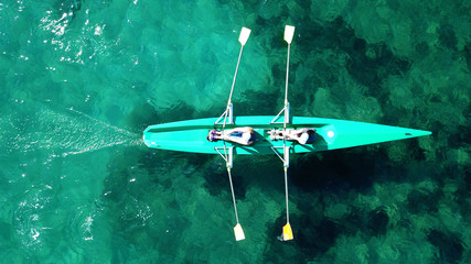 Fototapeta premium Aerial drone bird's eye view of sport canoe operated by 2 young women in turquoise clear waters