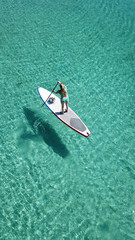 Fototapeta premium Aerial photo of woman on sup or paddle surf in tropical caribbean turquoise clear water beach