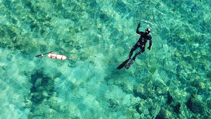 Aerial drone bird's eye view photo of scuba diver in tropical rocky sea with turquoise clear waters