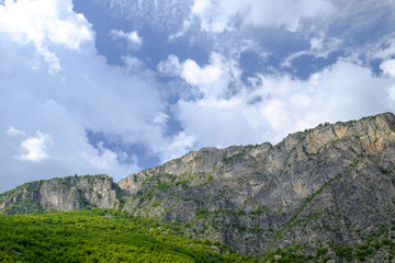 Obraz premium Mountain ridge surrounded by green on a cloudy sky 1