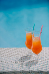 close-up view of summer cocktails with drinking straws at pool