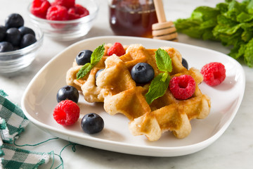 Traditional belgian waffles with blueberries and raspberries on white marble