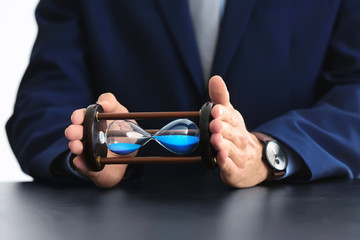 Man holding hourglass over table. Time management concept