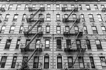 A fire escape of an apartment building in New York city. Graphical black and white image.