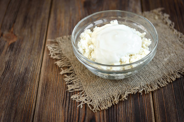 Cottage cheese with sour cream, cinnamon and almond on dark wooden background. Healthy diet food. Protein meal.