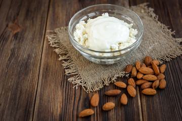 Cottage cheese with sour cream, cinnamon and almond on dark wooden background. Healthy diet food. Protein meal.