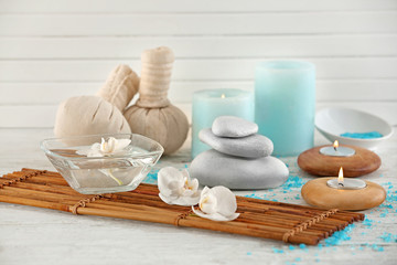 Bowl of water with flowers and bamboo tray on table