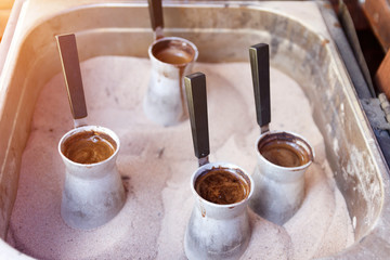 Turks with coffee on hot sand. Preparing coffee in jezva in sand. Turkish method of preparing coffee. Eastern coffee