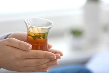 Young woman with cup of hot tea at home, closeup