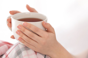 Young woman with cup of hot tea at home, closeup