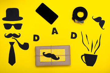 Happy Father's Day.Postcard and a gift for dad.The hat, glasses, mustache, smoking pipe ,belt, tablet , bow tie,phone and cup coffee, on a yellow paper background.