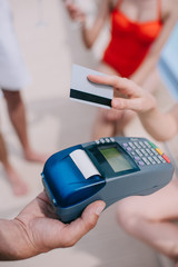 close-up partial view of person paying with credit card on beach