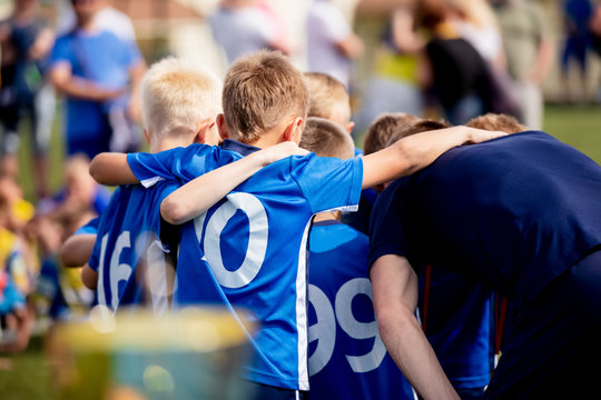 Young football players in blue jersey sportswear. Group photo with football coach. Young sports team with football coach. Pep talk with coach before the final match. Football school tournament © matimix