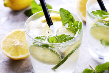 Two glasses of refreshing non alcoholic mojito lemonade drink with organic lemon, lime slices, mint...