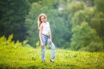 portrait of little beautiful stylish kid girl on green forest background