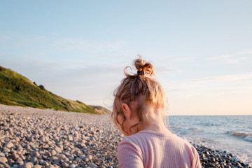 Kleines Mädchen läuft bei Sonnenuntergang am Strand entlang